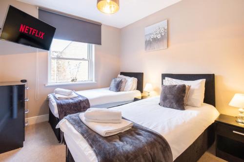 a bedroom with two beds and a tv in it at Velvet 2-bedroom apartment, Conduit Lane, Hoddesdon in Hoddesdon