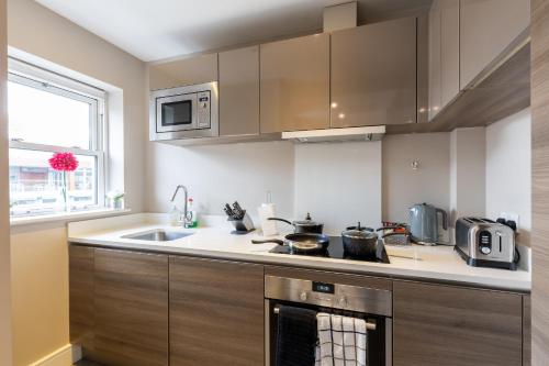 Il comprend une cuisine équipée d'un évier et d'une cuisinière. dans l'établissement Velvet 2-bedroom apartment, Conduit Lane, Hoddesdon, à Hoddesdon