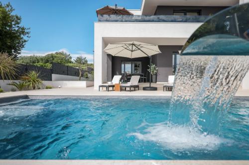 una piscina con una fuente de agua frente a una casa en Villa Dekorti - Adriatic Luxury Villas, en Kožino