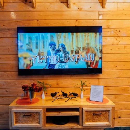 a flat screen tv on a wall with a table at DSR Wooden Cottages in Hyderabad