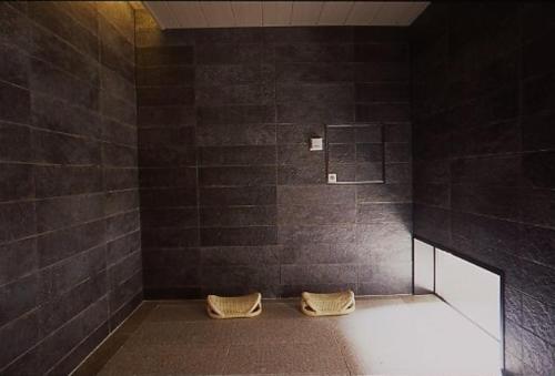 a black tiled bathroom with two towels on the floor at Ryokan Sumiya Kihoan in Kameoka