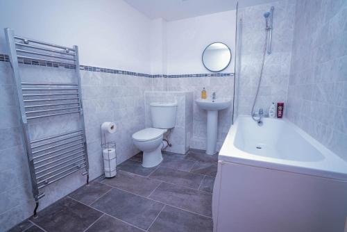 a bathroom with a toilet and a sink and a tub at Beautiful 2 Bedroom,freeParking L Buzzard in Leighton Buzzard