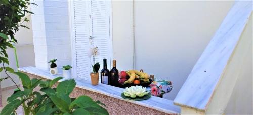 a basket of fruit and wine bottles on a window sill at Eleni Apartments Sant George Beach in Agios Georgios