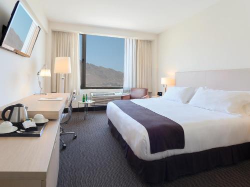 Habitación de hotel con cama y ventana grande en Spark Hoteles en Antofagasta