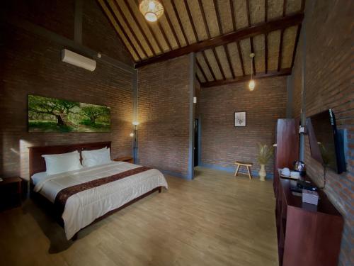 a bedroom with a bed and a television in it at Kayon Griya Osing Villa - Ijen in Licin