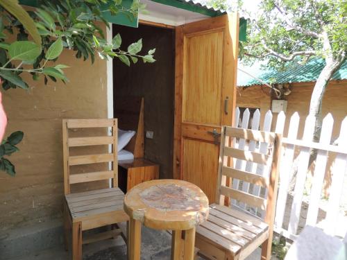 2 sedie in legno, un tavolo e una porta in legno di Enthralling Escapes Nature Stay and Trek a Manāli