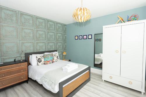 a bedroom with blue walls and a bed and a dresser at Sunbeam Cottage sleeps 10 in Whitstable