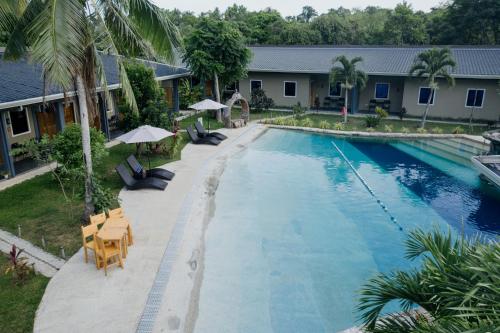 a swimming pool with chairs and umbrellas next to a house at Hidden Lagoon Resort in Panglao