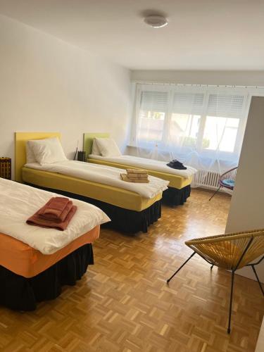 een kamer met 3 bedden en een stoel bij Casa Kromatica in Locarno