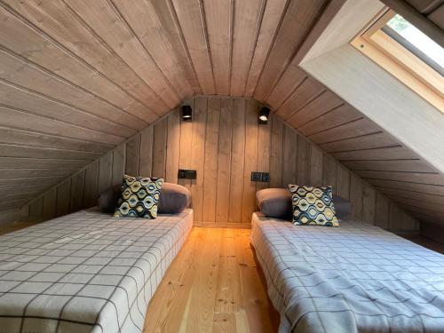 two beds in a room with a wooden ceiling at Szopa_Narie in Gulbity