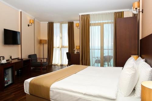 a hotel room with a large bed and a desk at Hotel Corner Inn in Batumi