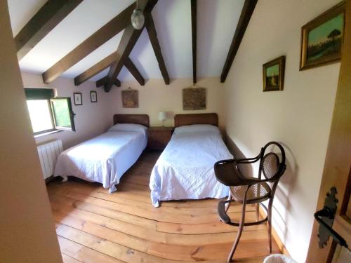 a bedroom with two beds and a chair in it at La Cirujana de Gredos in San Esteban del Valle