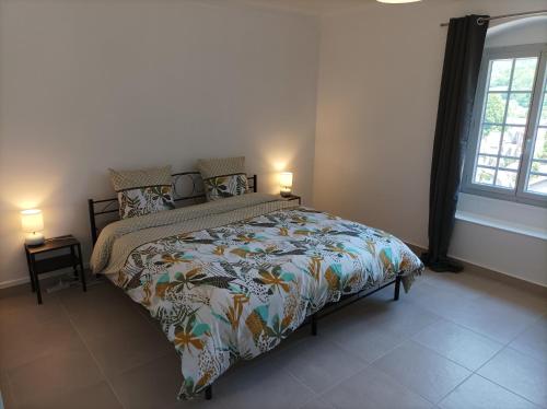 1 dormitorio con 1 cama con edredón colorido y 2 lámparas en O'Couvent - Appartement 66 m2 - 2 chambres - A523, en Salins-les-Bains