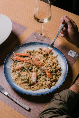 a plate of shrimp and pasta with a glass of wine at 3 Sixty Hotel & Suites in Nafplio