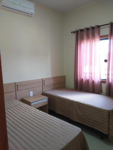 um quarto com duas camas e uma janela com cortinas cor-de-rosa em Casa de praia no Condomínio Guaratiba, Prado-BA em Prado