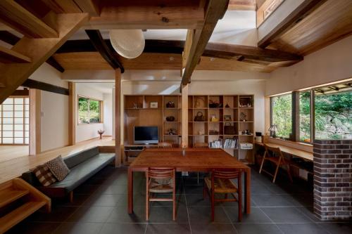 ein Wohnzimmer mit einem Holztisch und einem Sofa in der Unterkunft Casa KitsuneAna The Satoyama experience in a Japanese-style modernized 100-year-old farmhouse in Akaiwa