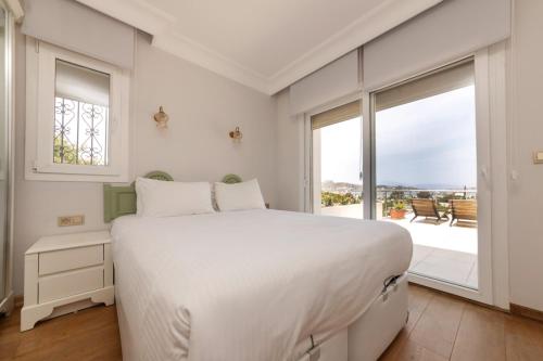 a white bedroom with a large bed and a large window at YALIKAVAK VILLA MAGNOLIA in Bodrum City