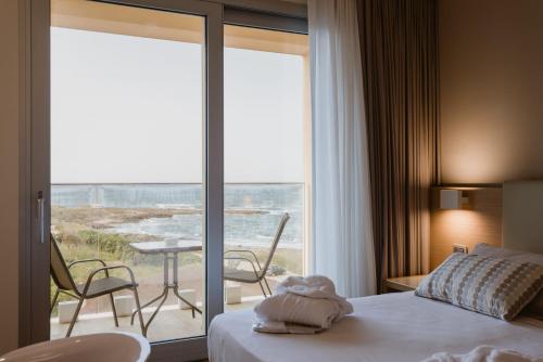 a hotel room with a bed and a view of the ocean at Hotel Calabona in Alghero