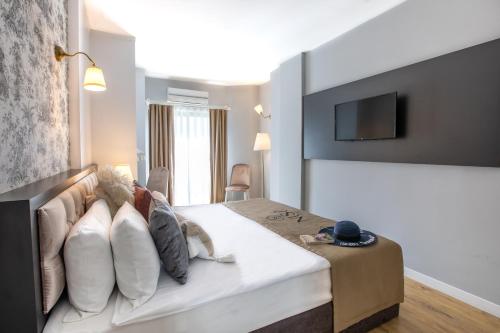 a bedroom with a bed with pillows and a tv at Niss Lara Hotel in Antalya