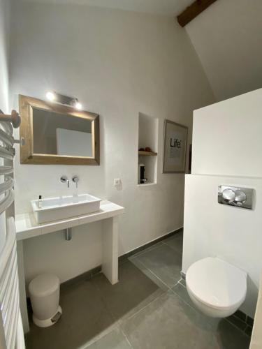 La salle de bains blanche est pourvue d'un lavabo et de toilettes. dans l'établissement Les Bergeries de Figari, à Figari