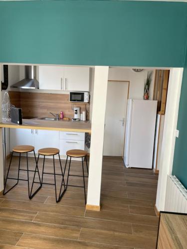 une cuisine avec un comptoir et des tabourets dans une pièce dans l'établissement Le LH CENTRE VILLE, au Havre