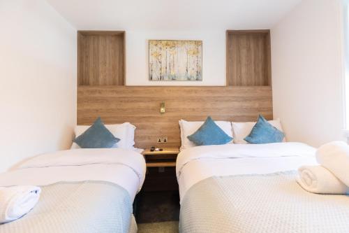 2 camas en una habitación de hotel con almohadas azules en The Chapter - Griffin House Hotel, en Londres