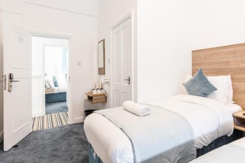 a white bedroom with two beds and a hallway at The Chapter Hotels - Griffin House in London
