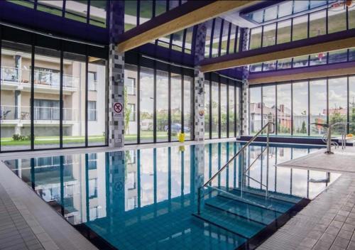 a large swimming pool in a building with windows at Apartament 5 mórz in Sianozety