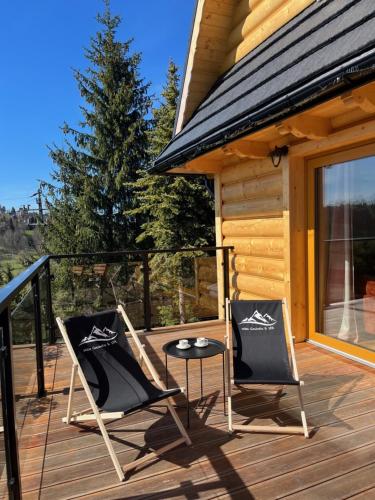 twee stoelen en een tafel op het dek van een cabine bij Willa Gocówka & SPA in Bukowina Tatrzańska