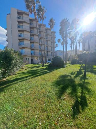 a grassy area with palm trees and a building at Ostella Spa & Resort in Bastia