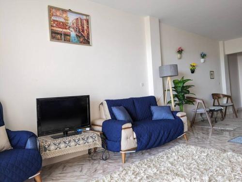 a living room with a blue couch and a tv at Spacious 3 bedroom apartment with a sea view. in Dawwār Abū Maḩrūs