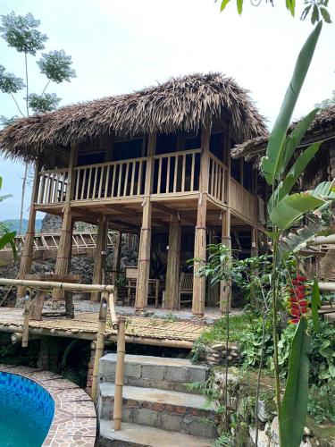 a house with a straw roof and a swimming pool at MAI HICH FARMSTAY 2 in Mai Hạ