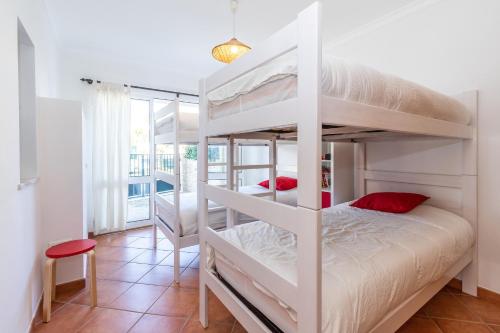 a bedroom with two bunk beds and a red stool at Moradia Rainbow by ALGARVEMANTA in Manta Rota