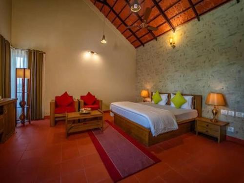 a bedroom with a bed and a couch and a table at Niraamaya Retreats Vaidekam, Kannur in Kannur