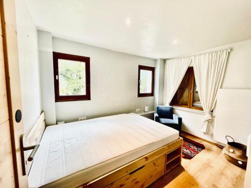 a bedroom with a large white bed and a chair at Chalet in green, sunny and quite spot 5’ from center in Chamonix-Mont-Blanc
