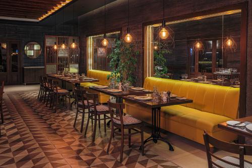 a restaurant with tables and chairs and a yellow couch at JAZ Aquaviva in Hurghada