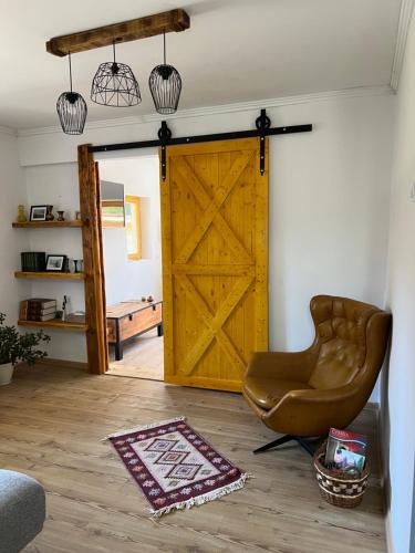 a living room with a wooden door and a chair at Nantucket GuestHouse in Vrbas