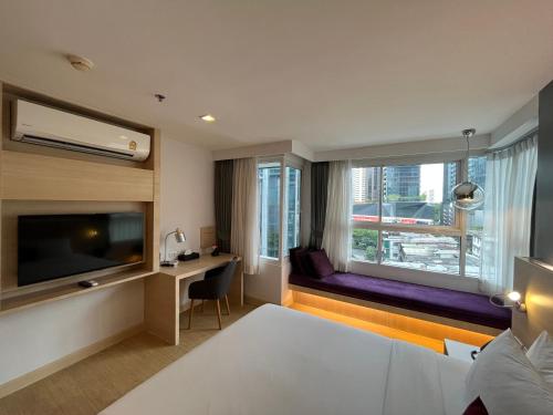 バンコクにあるアリゼ ホテル スクンビットのベッドと大きな窓が備わるホテルルームです。