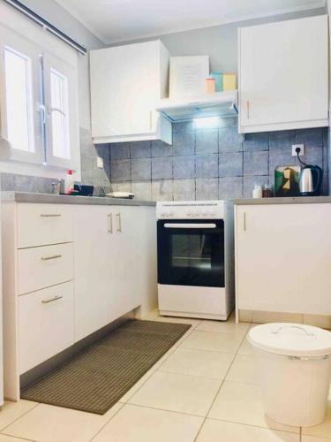 a kitchen with white cabinets and a stove top oven at New, Modern and Cozy apartment in Gavrio in Gavrion
