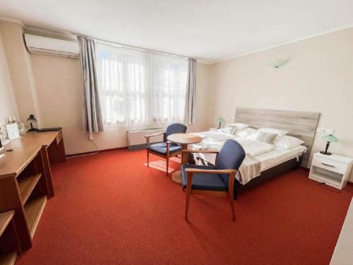 a bedroom with a bed and a table and chairs at Hotel Unicornis in Eger