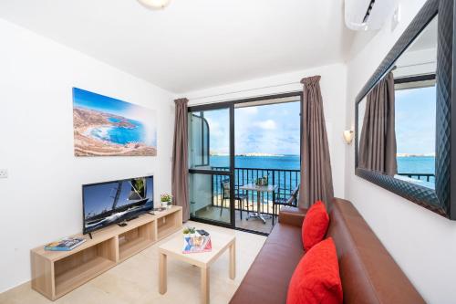 a living room with a couch and a large window at Islet Promenade Seafront 1 Bedroom Apartment with sea view balcony by Getawaysmalta in St. Paul's Bay