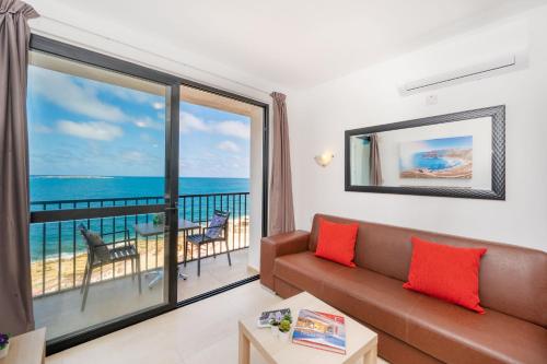 a living room with a couch and a view of the ocean at Islet Promenade Seafront 1 Bedroom Apartment with sea view balcony by Getawaysmalta in St Paul's Bay