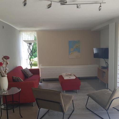 a living room with a red couch and a tv at Bungalow Veluwemeer in Ermelo