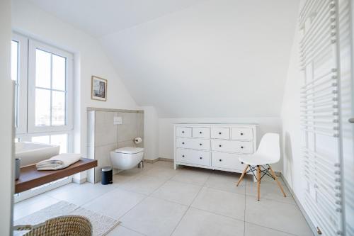 a white bathroom with a sink and a toilet at Familienurlaub im Hus in de Sünn in Puddemin