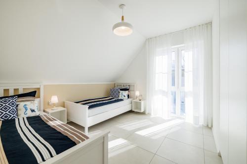 a white bedroom with a bed and a window at Familienurlaub im Hus in de Sünn in Puddemin