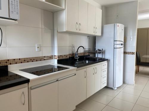 a kitchen with white cabinets and a white refrigerator at Hotel APART Zuccolotto 303 in Aracruz