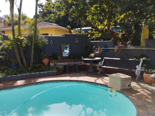 a swimming pool in a backyard with a bench and a table at Tuksumduin in Ballito