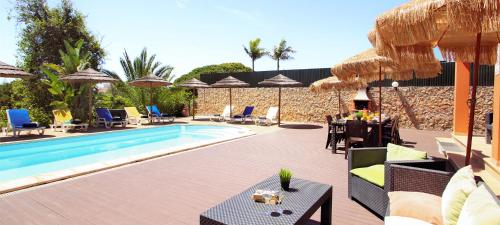 アルブフェイラにあるVilla California by Algarve Vacationのプールサイドのテーブルと椅子付きのスイミングプール
