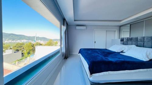 een slaapkamer met een bed en een groot raam bij Casa 3 quartos casal Alto Padrão Vista, SPA, Hidro e Piscina de vidro in Florianópolis