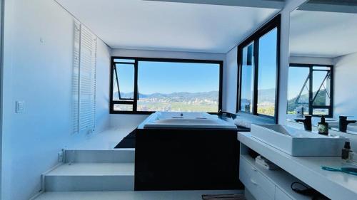 een grote badkamer met 2 wastafels en een groot raam bij Casa 3 quartos casal Alto Padrão Vista, SPA, Hidro e Piscina de vidro in Florianópolis